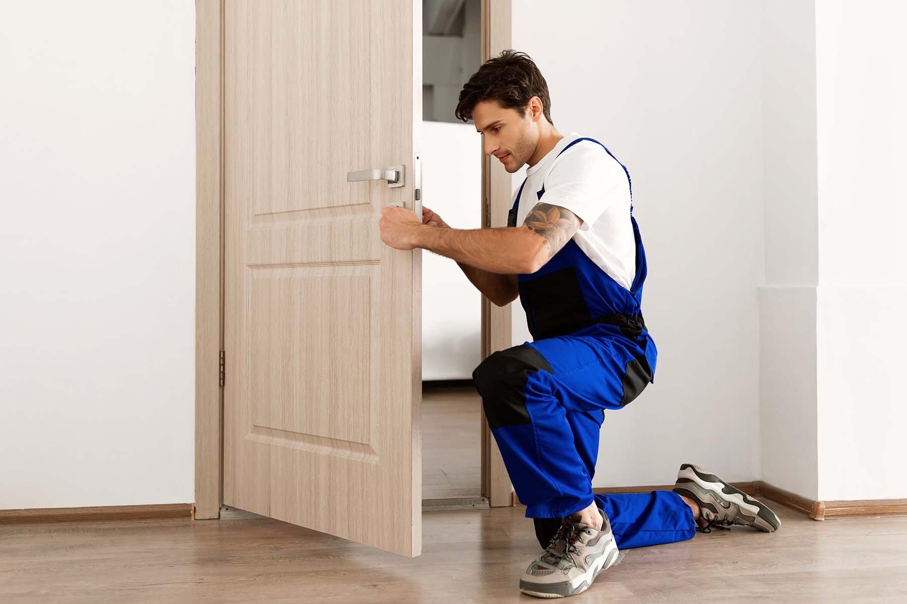 Man in workwear fixing a door handle.